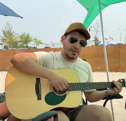 Daniel playing guitar on the beach